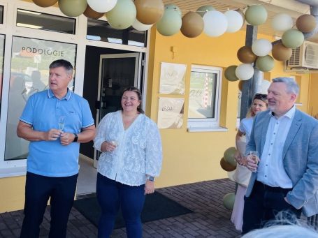 Martina Krouzek mit ihrem Mann Jan Krouzek (Familienteam hinter der Praxis) beim Fest Drei Personen stehen vor einem gelben Gebäude mit bunten Papierlaternen.